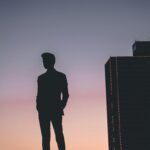 Silhouette of a man standing against a colorful Fort Worth sunset skyline, capturing urban tranquility.